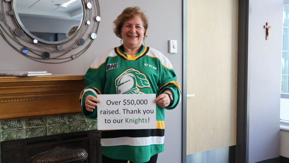 Dr Gillian Kernaghan wears a London knights jersey and holds up a sign thanking the hockey team