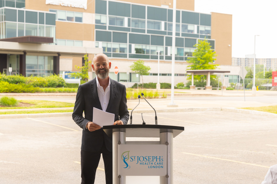 Ryan Finch at a podium in front of the Finch Family Mental Health Care Building
