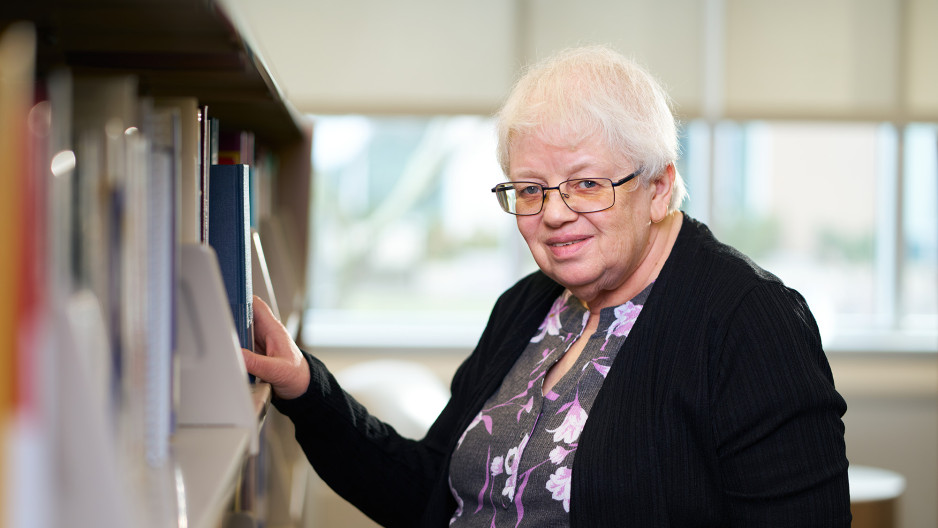 Christine Boyd beside a bookshelf