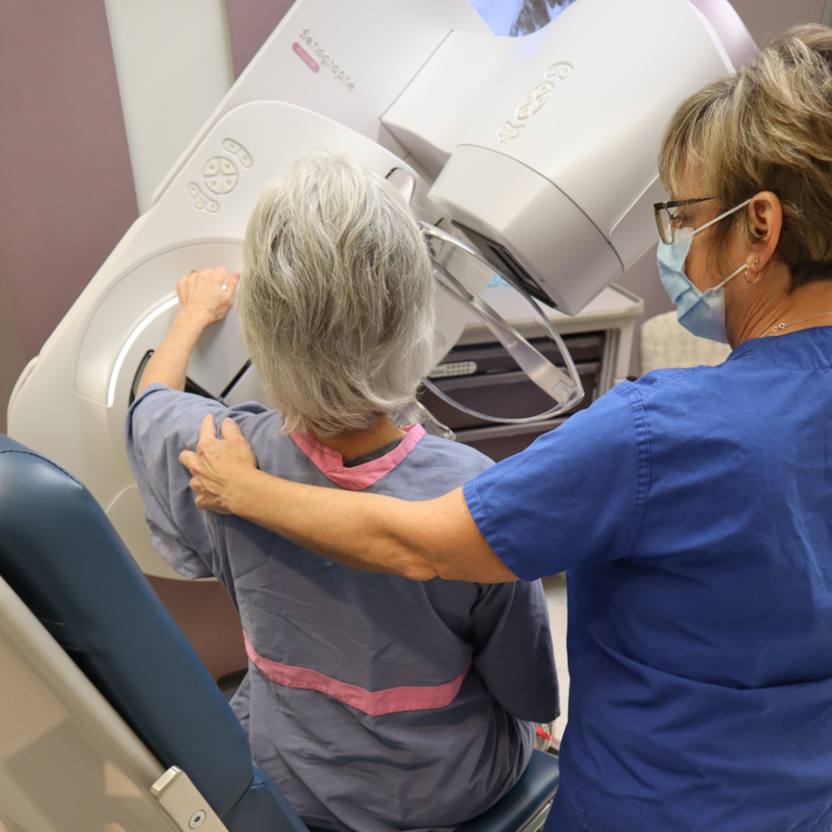 a nurse performs a mammogram on patient