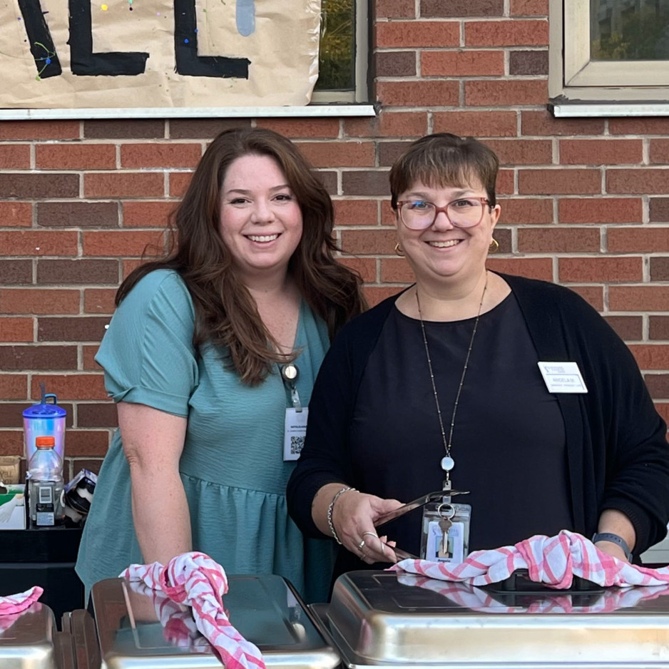 two female staff members getting ready to serve food from warming trays