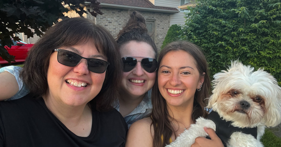 Three women and a dog smile at camera