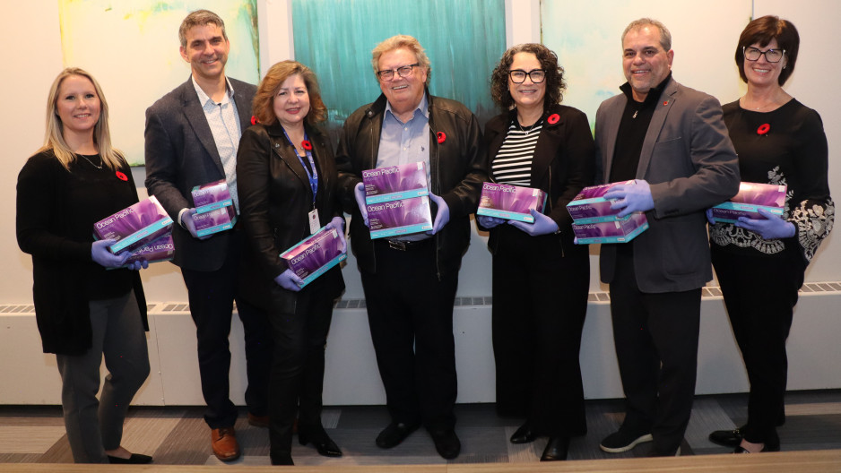 People standing with boxes of gloves and smiling