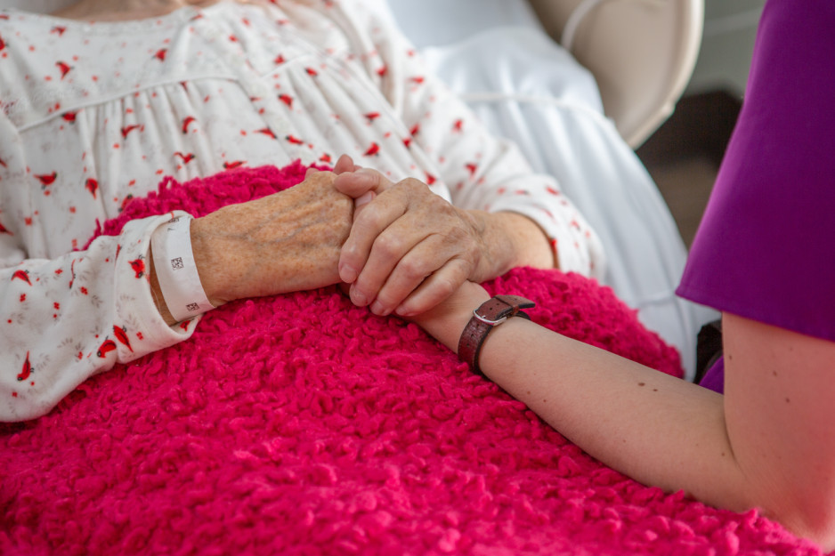 a patient and care provider hold each other's hand